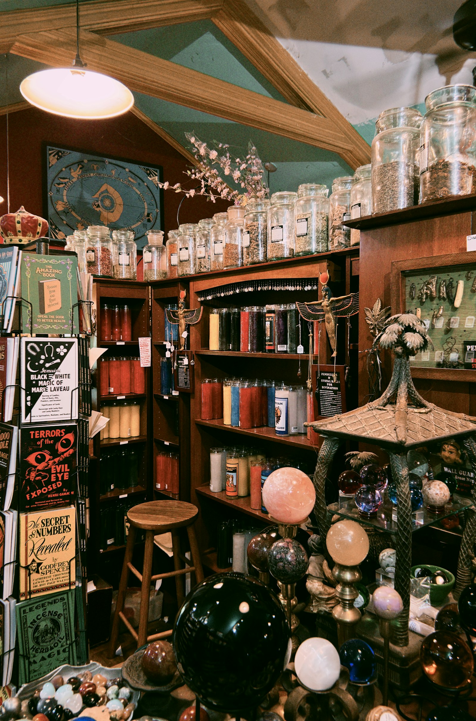 Crystal spheres, books, candles, and herbs in a shadowed apothecary