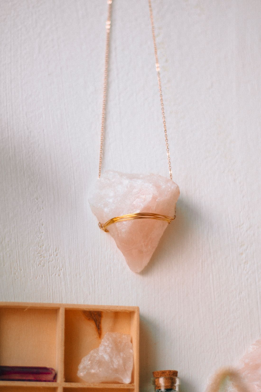 Pale crystal pendant hanging against a softly lit wall