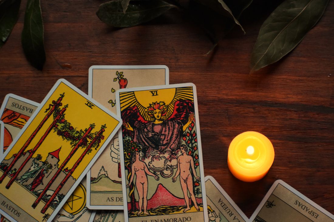 Tarot cards, candles, flowers, and crystals arranged on a table at night